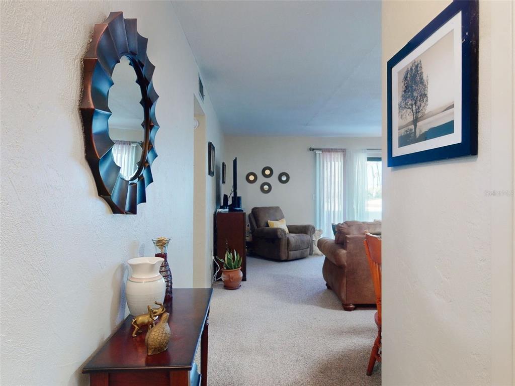 A view from a hallway into a carpeted living room with a brown recliner — 2101 N ATLANTIC AVENUE UNIT 10, DAYTONA BEACH, FL