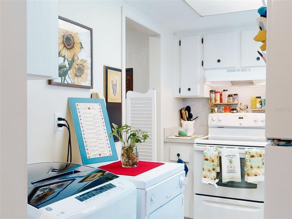 A laundry area with a white washer and dryer sits adjacent to a white kitchen — 2101 N ATLANTIC AVENUE UNIT 10, DAYTONA BEACH, FL