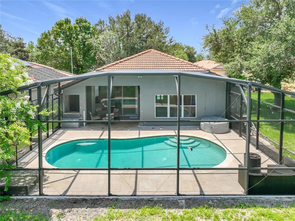 A backyard swimming pool is enclosed by a screened lanai behind a single-story house — 5915 BUFORD STREET, ORLANDO, FL