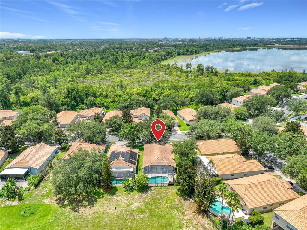 An aerial view shows a suburban neighborhood with houses, swimming pools, and a nearby lake — 5915 BUFORD STREET, ORLANDO, FL