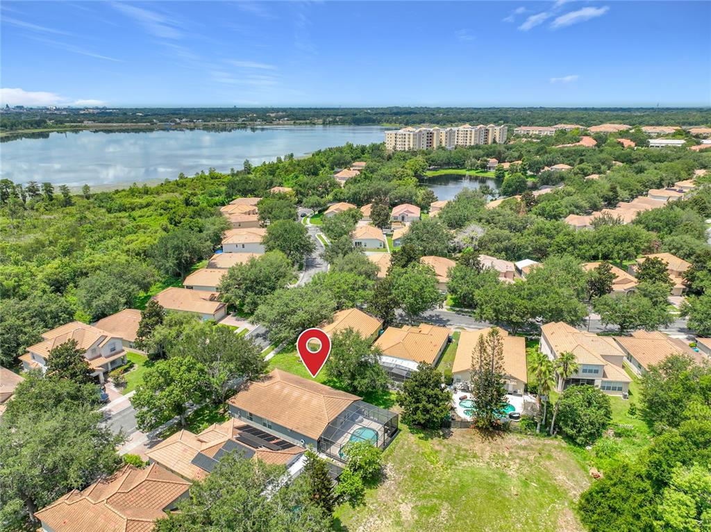 An aerial view shows a suburban neighborhood with houses, swimming pools, and a large lake — 5915 BUFORD STREET, ORLANDO, FL