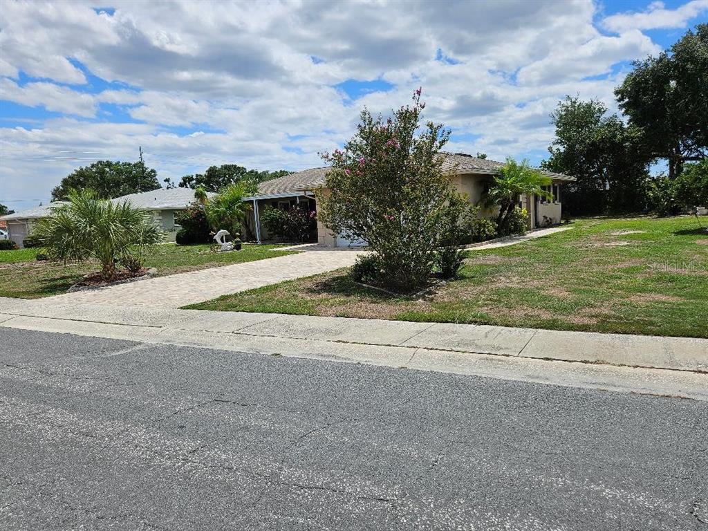 A single-story house with a paved driveway and a large flowering bush in the front yard — 708 BRANNEN CIRCLE, SUN CITY CENTER, FL