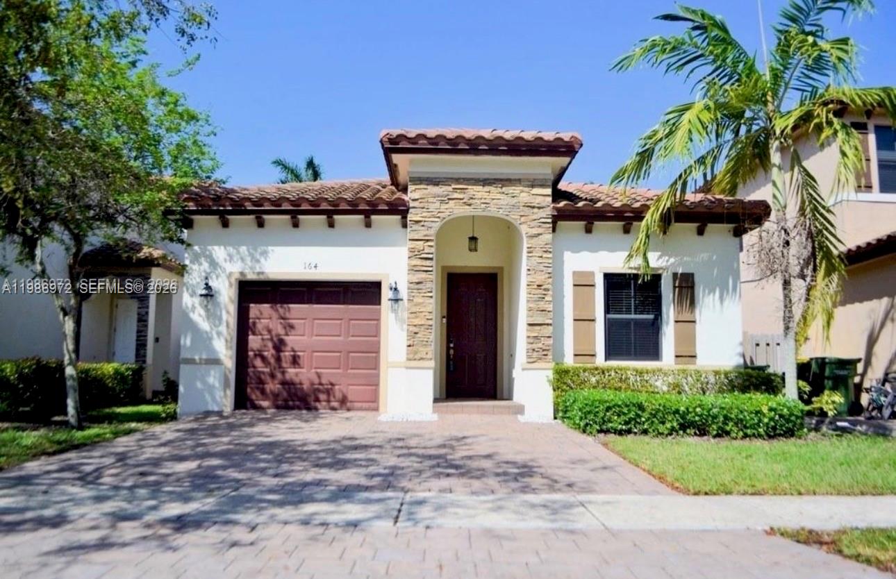 A single-story house with a stone-accented entryway, a brown garage door, and a tile roof — 164 NE 23rd Ter, Homestead FL 33033, HOMESTEAD, FL