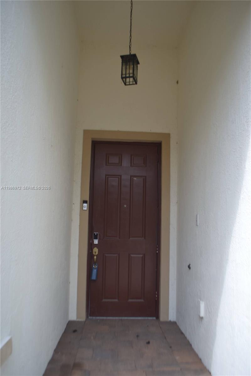 A brown front door is set within a recessed entryway with white stucco walls — 164 NE 23rd Ter, Homestead FL 33033, HOMESTEAD, FL