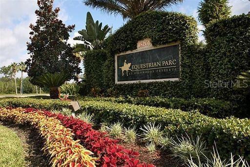 A stone monument sign for Equestrian Parc is surrounded by manicured hedges and colorful landscaping — 18557 BRIDLE CLUB DRIVE UNIT 18557, TAMPA, FL