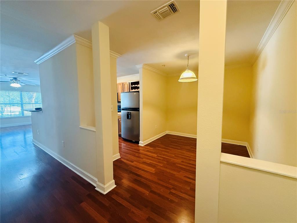 A dining area with a pendant light and hardwood floors leads to a kitchen — 18557 BRIDLE CLUB DRIVE UNIT 18557, TAMPA, FL