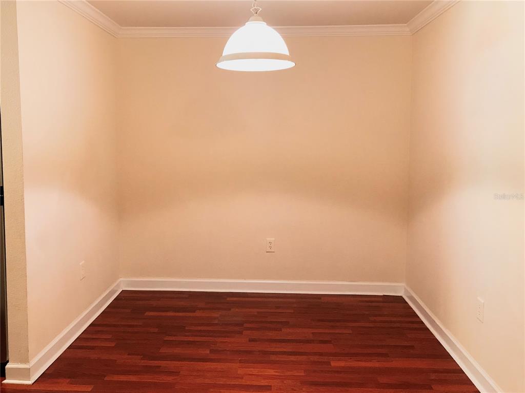 An empty dining area features dark wood-look flooring, beige walls, and a white pendant light — 18557 BRIDLE CLUB DRIVE UNIT 18557, TAMPA, FL