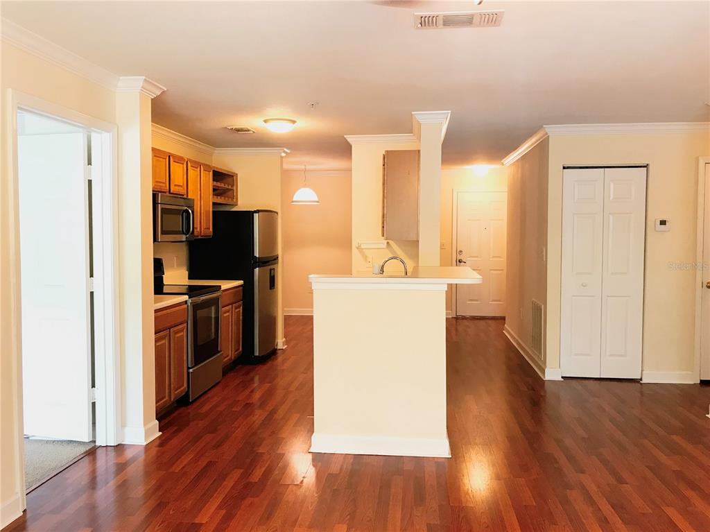 A kitchen with wood cabinets, stainless steel appliances, and hardwood floors opens to a hallway — 18557 BRIDLE CLUB DRIVE UNIT 18557, TAMPA, FL