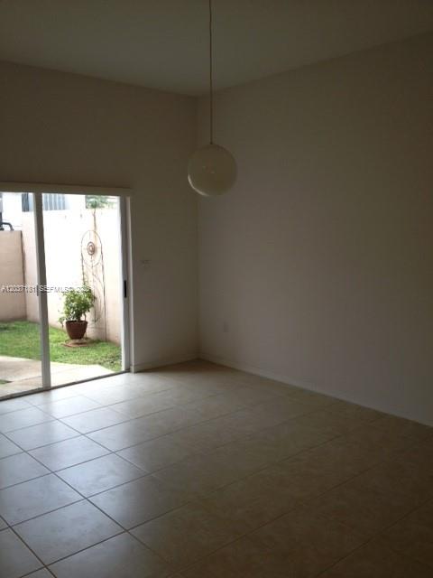 A room with light-colored tile flooring, a hanging globe light, and a sliding glass door — 1657 SE 23rd Way # 1657, Homestead FL 33035, HOMESTEAD, FL