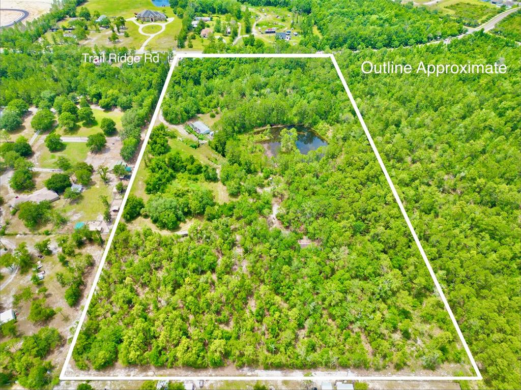 An aerial view shows a large, wooded plot of land with a small pond — 3622 TRAIL RIDGE ROAD, MIDDLEBURG, FL