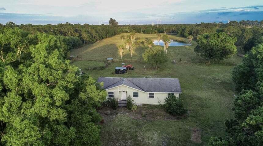 An aerial view of a single-story house situated on a large, grassy rural lot — 11470 Carlton Road, Port St. Lucie FL 34987, PORT ST. LUCIE, FL