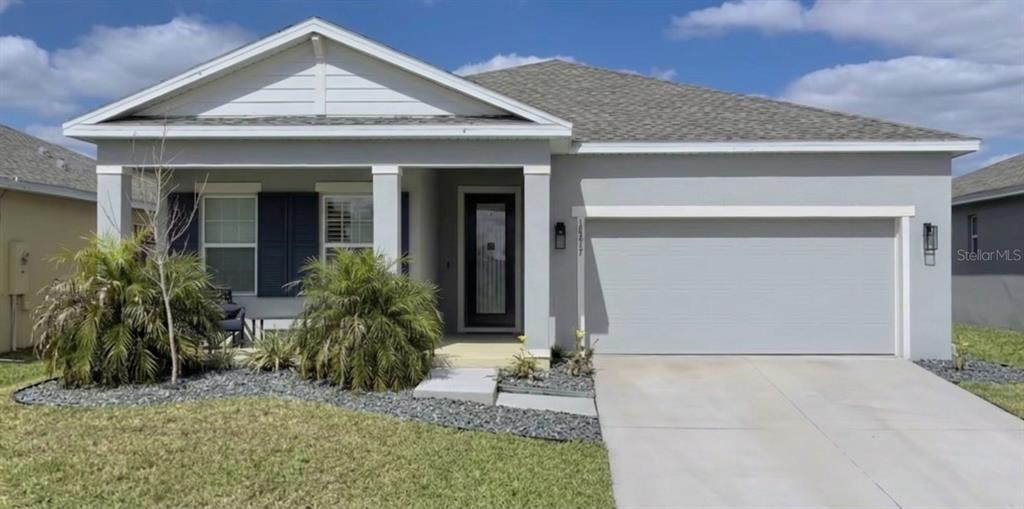 A single-story house with a gray stucco exterior, a two-car garage, and a covered entryway — 18217 FALLING PINE NEEDLE LANE, LAND O LAKES, FL