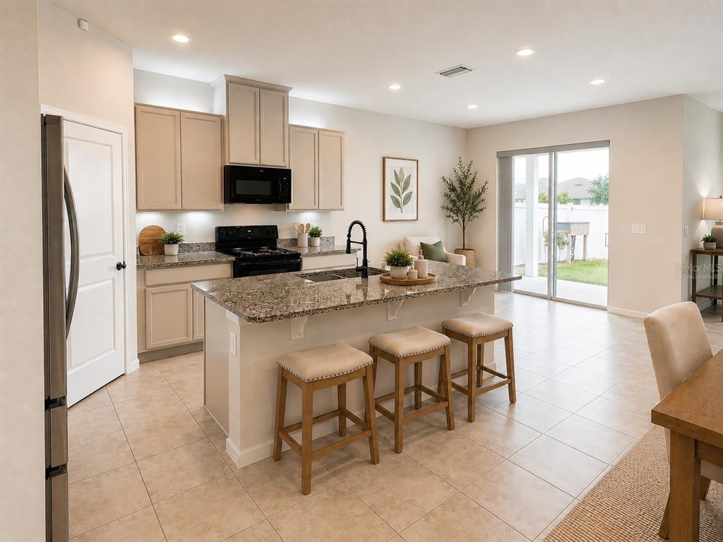 A kitchen with beige cabinets, granite countertops, a center island with stools, and tile flooring — 18217 FALLING PINE NEEDLE LANE, LAND O LAKES, FL