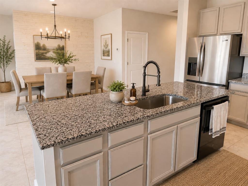 A kitchen island with a granite countertop and sink overlooks a dining area with shiplap — 18217 FALLING PINE NEEDLE LANE, LAND O LAKES, FL