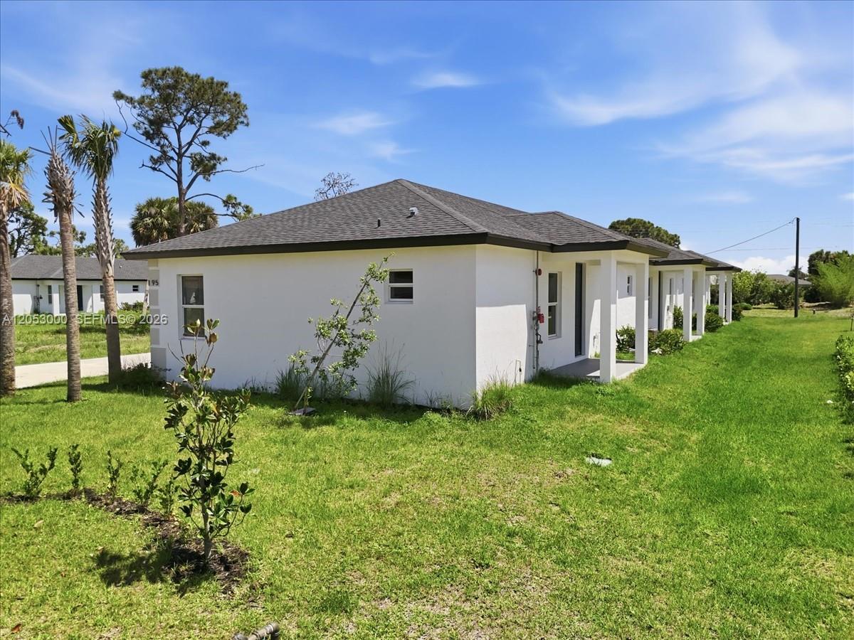 A white, single-story residential building with a dark shingled roof sits on a grassy lot — 195 Rotonda # C, Port Charlotte FL 33947, PORT CHARLOTTE, FL