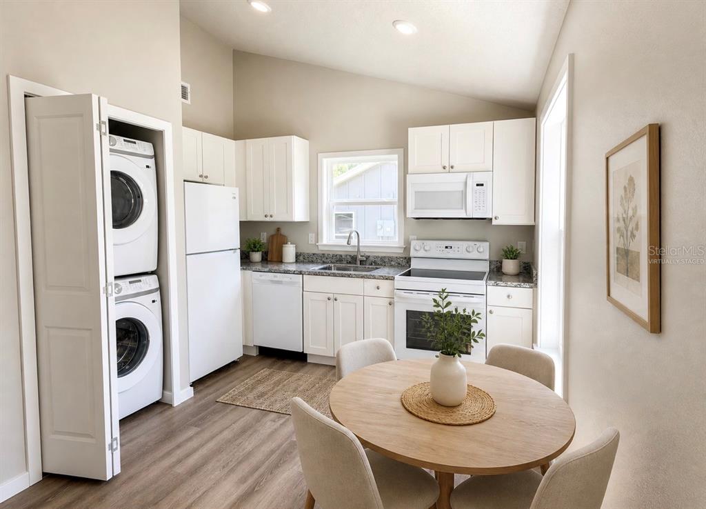 A kitchen with white cabinets, stainless appliances, a stacked washer-dryer, and a round dining table — 357 N MAIN AVENUE, GROVELAND, FL