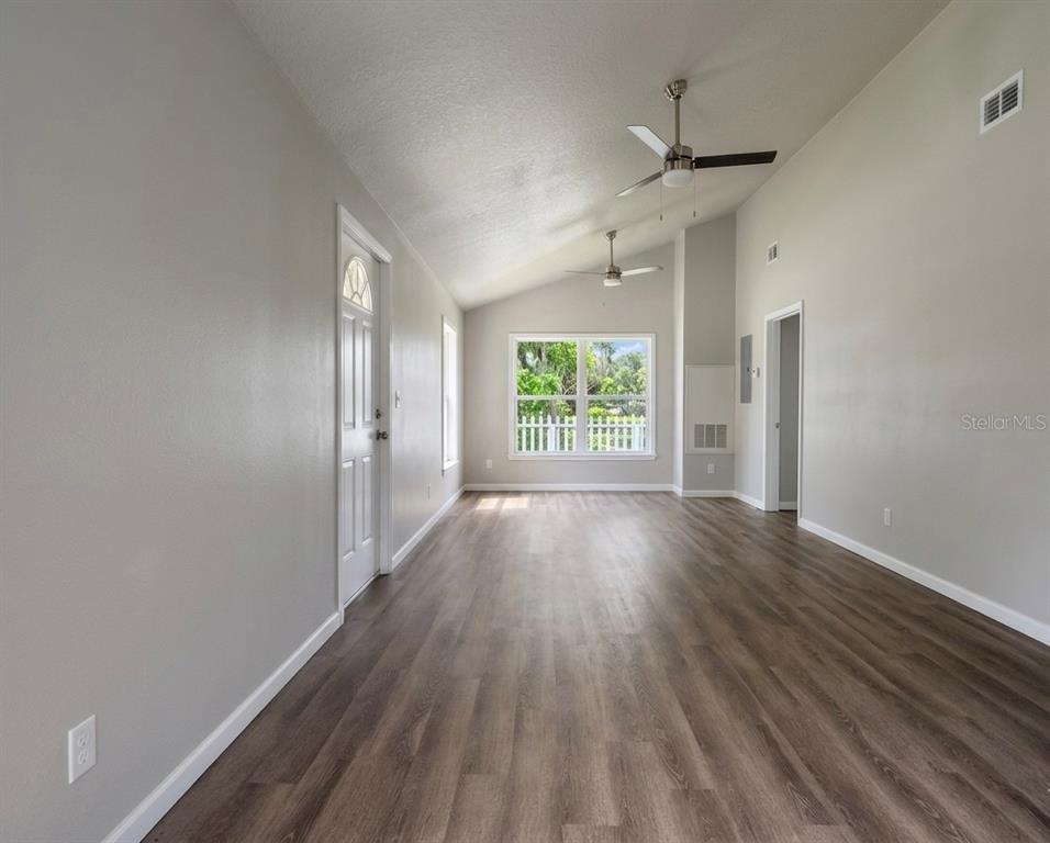 An empty room with light gray walls, vaulted ceilings, ceiling fans, and wood-look flooring — 357 N MAIN AVENUE, GROVELAND, FL