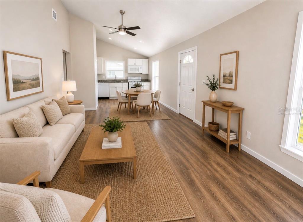 This open-concept living and dining area features light-colored walls, wood-look flooring, and a vaulted ceiling — 357 N MAIN AVENUE, GROVELAND, FL