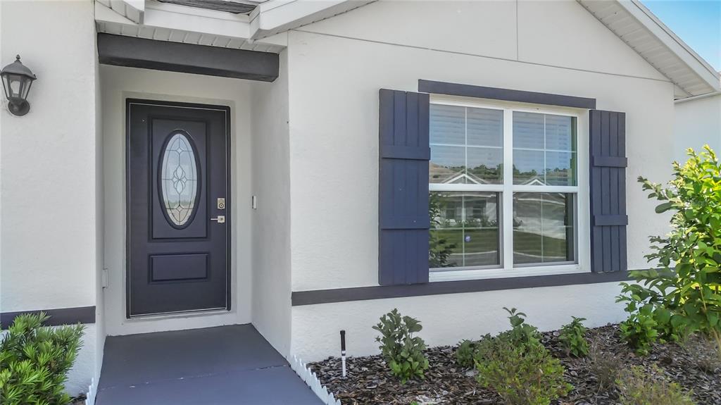The exterior of a house features a dark front door, blue shutters, and landscaping — 13677 SW 69TH TERRACE, OCALA, FL