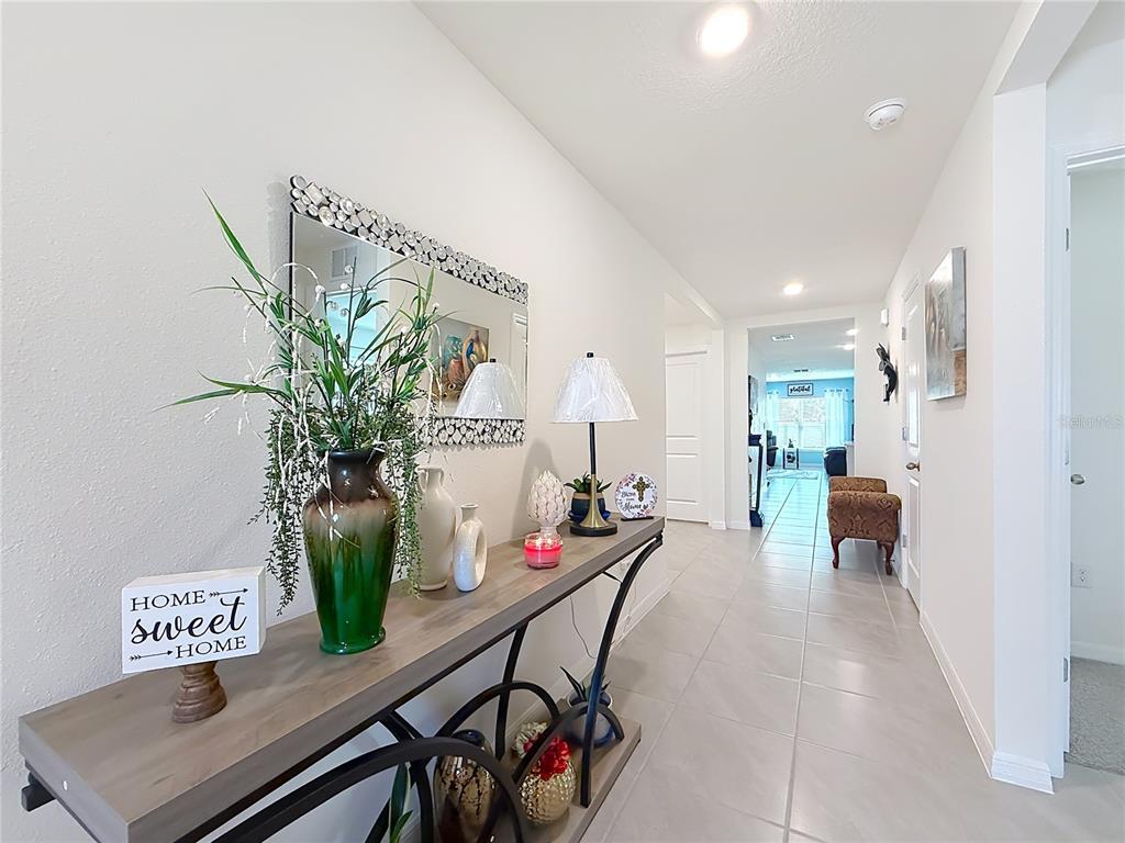 A hallway features a console table with decor, a mirror, and tile flooring — 13677 SW 69TH TERRACE, OCALA, FL