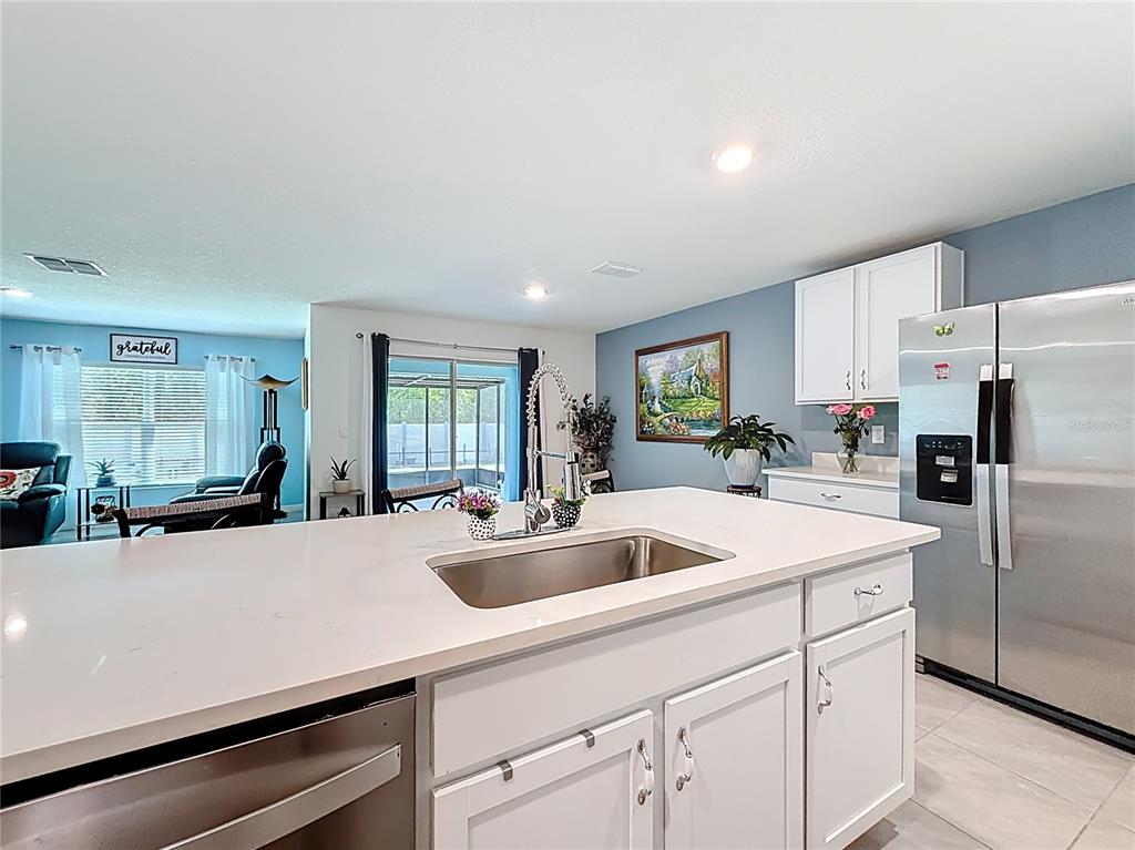 A kitchen island with a stainless steel sink sits before white cabinets and stainless appliances — 13677 SW 69TH TERRACE, OCALA, FL