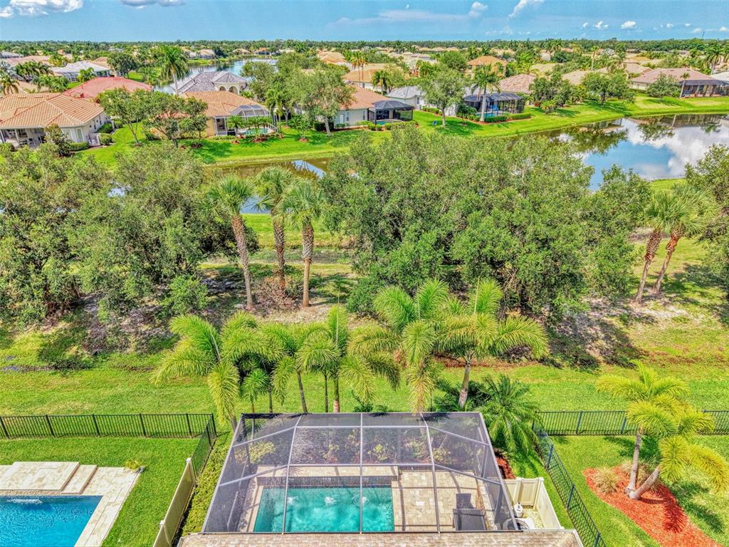 An aerial view of a backyard swimming pool with a screen enclosure and surrounding landscaping — 8467 NANDINA DRIVE, SARASOTA, FL