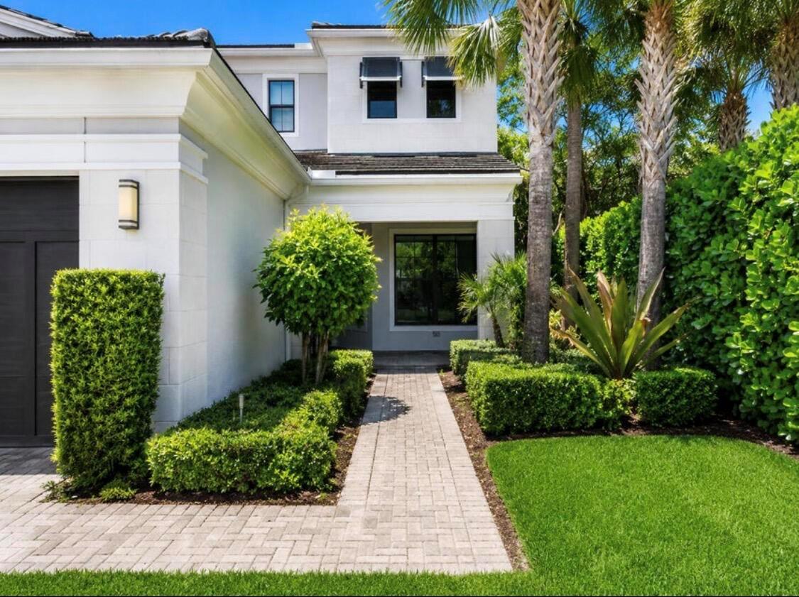 A paved walkway leads to the entrance of a two-story white house with landscaping — 5603 Delacroix Terrace, Palm Beach Gardens FL 33418, PALM BEACH GARDENS, FL