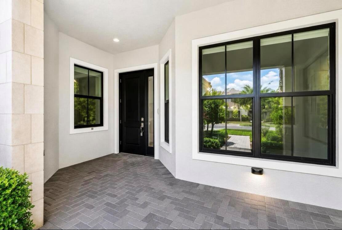A covered entryway features a black front door, large windows, and gray brick pavers — 5603 Delacroix Terrace, Palm Beach Gardens FL 33418, PALM BEACH GARDENS, FL