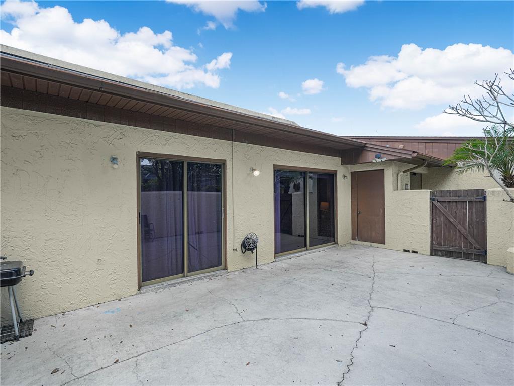 A concrete patio sits in front of a house with two sliding glass doors — 1880 N CRYSTAL LAKE DRIVE UNIT 18, LAKELAND, FL