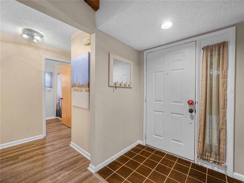 An entryway features a white front door, tiled floor, and a hallway with wood flooring — 1880 N CRYSTAL LAKE DRIVE UNIT 18, LAKELAND, FL