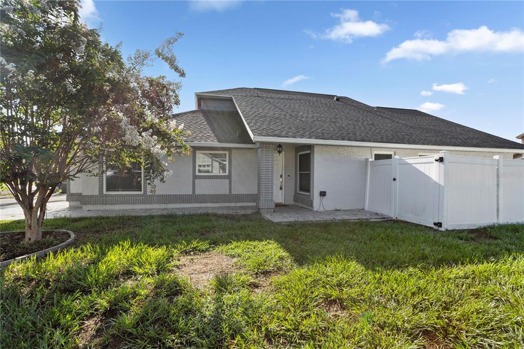 The exterior of a single-story house features a white stucco facade, brick accents, and a lawn — 3343 BUFFAM PLACE, CASSELBERRY, FL