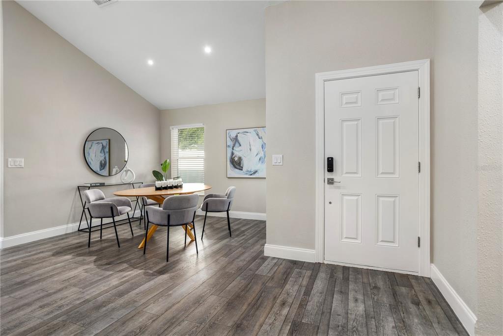 A dining area with wood-look flooring, a round table, and a white front door — 3343 BUFFAM PLACE, CASSELBERRY, FL
