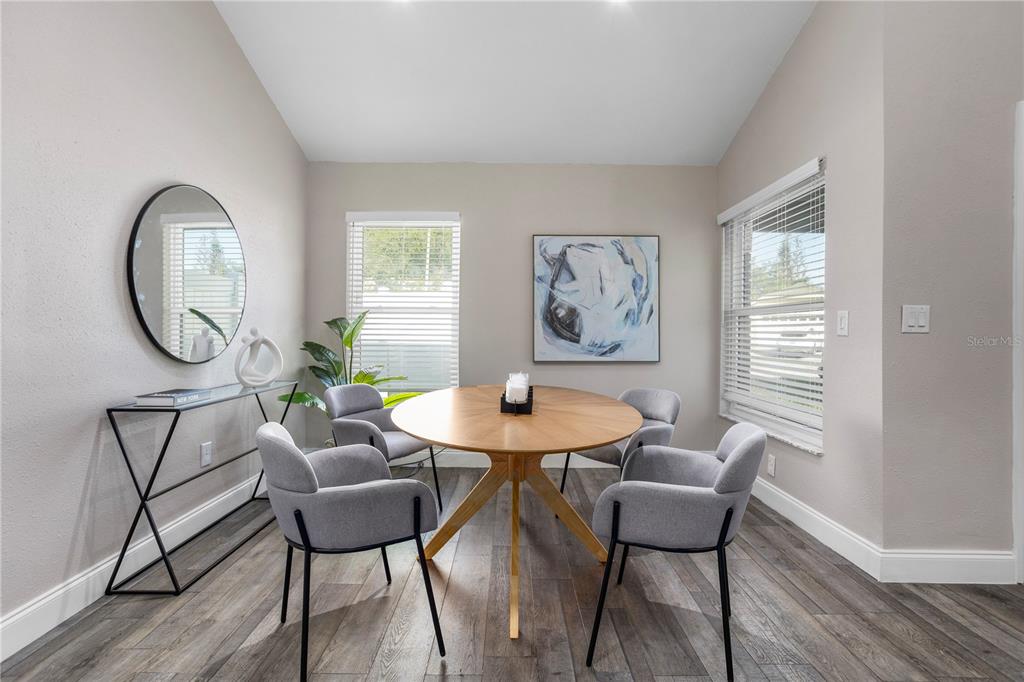A dining room features a round wooden table, four gray chairs, and a wall mirror — 3343 BUFFAM PLACE, CASSELBERRY, FL