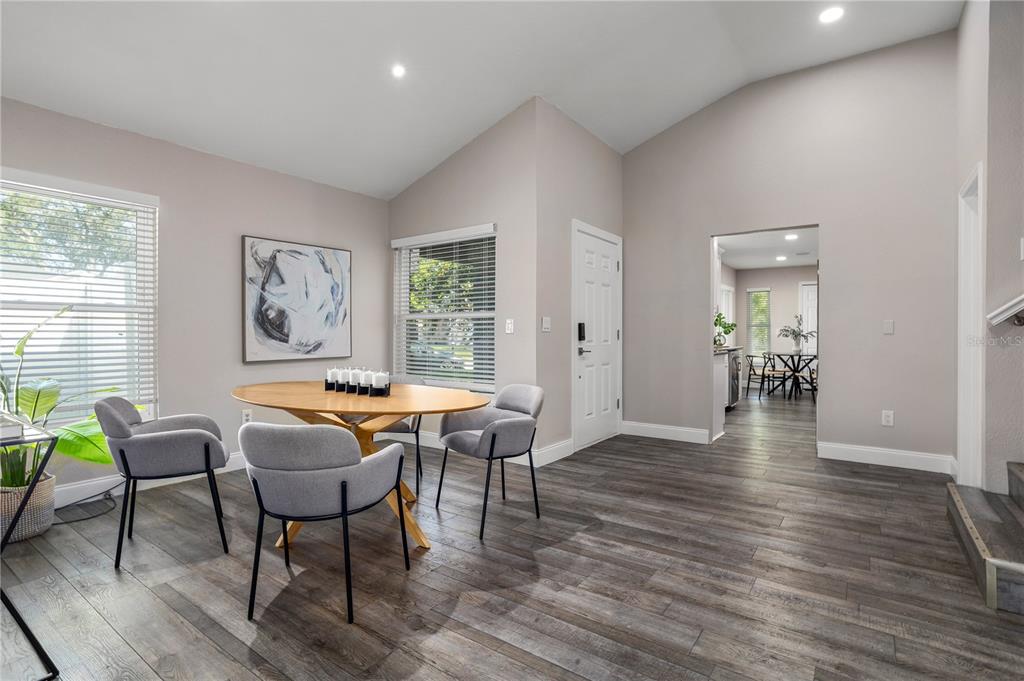 A dining area with a round wooden table, grey chairs, and dark wood-look flooring — 3343 BUFFAM PLACE, CASSELBERRY, FL