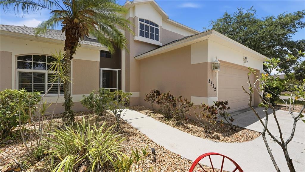 A tan two-story house features a garage, a palm tree, and a stone-covered front yard — 8222 HAVEN HARBOUR WAY, BRADENTON, FL