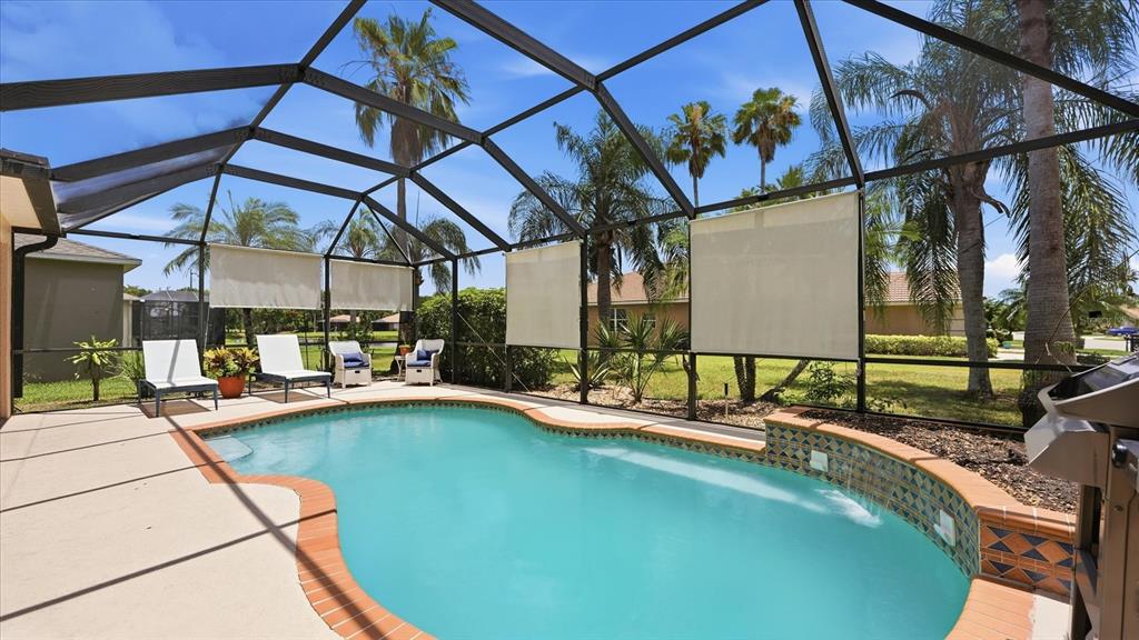 A screened-in patio features a swimming pool with a tiled spillover fountain and lounge chairs — 8222 HAVEN HARBOUR WAY, BRADENTON, FL