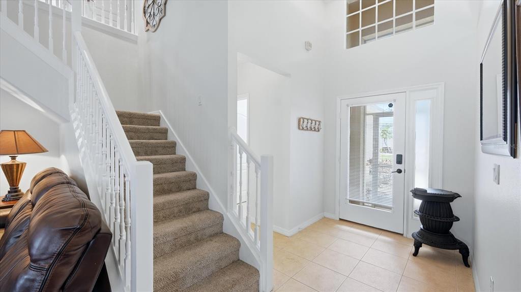 A bright entryway features a carpeted staircase, tile flooring, and a white front door — 8222 HAVEN HARBOUR WAY, BRADENTON, FL