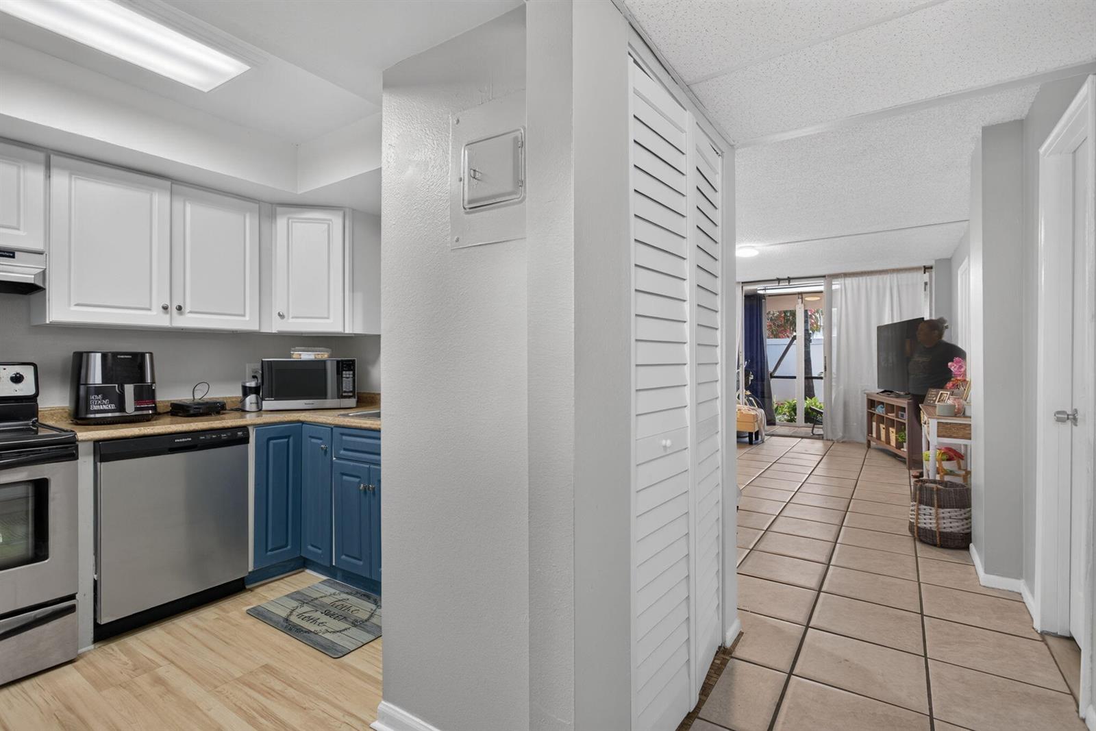 A kitchen with white and blue cabinets opens to a tiled living area with sliding doors — 118 Royal Pk Drive # 1f, Oakland Park FL 33309, OAKLAND PARK, FL