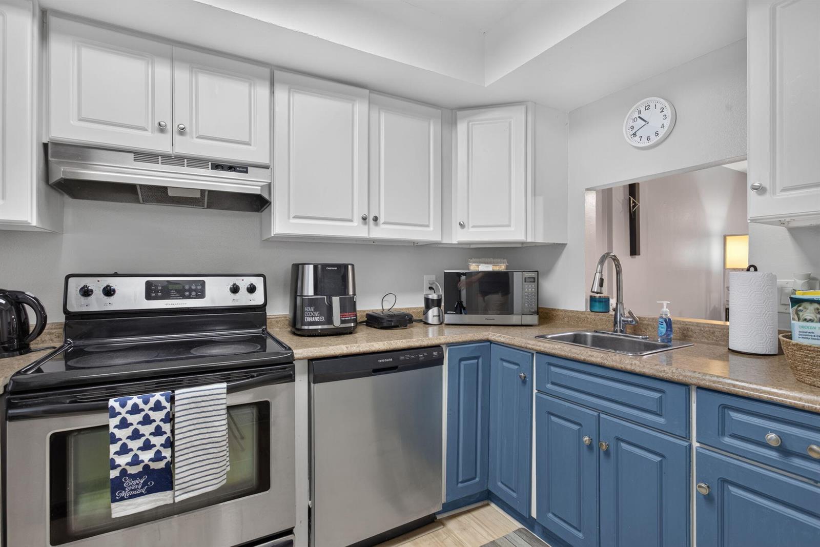 A kitchen features white upper cabinets, blue lower cabinets, stainless steel appliances, and tan countertops — 118 Royal Pk Drive # 1f, Oakland Park FL 33309, OAKLAND PARK, FL