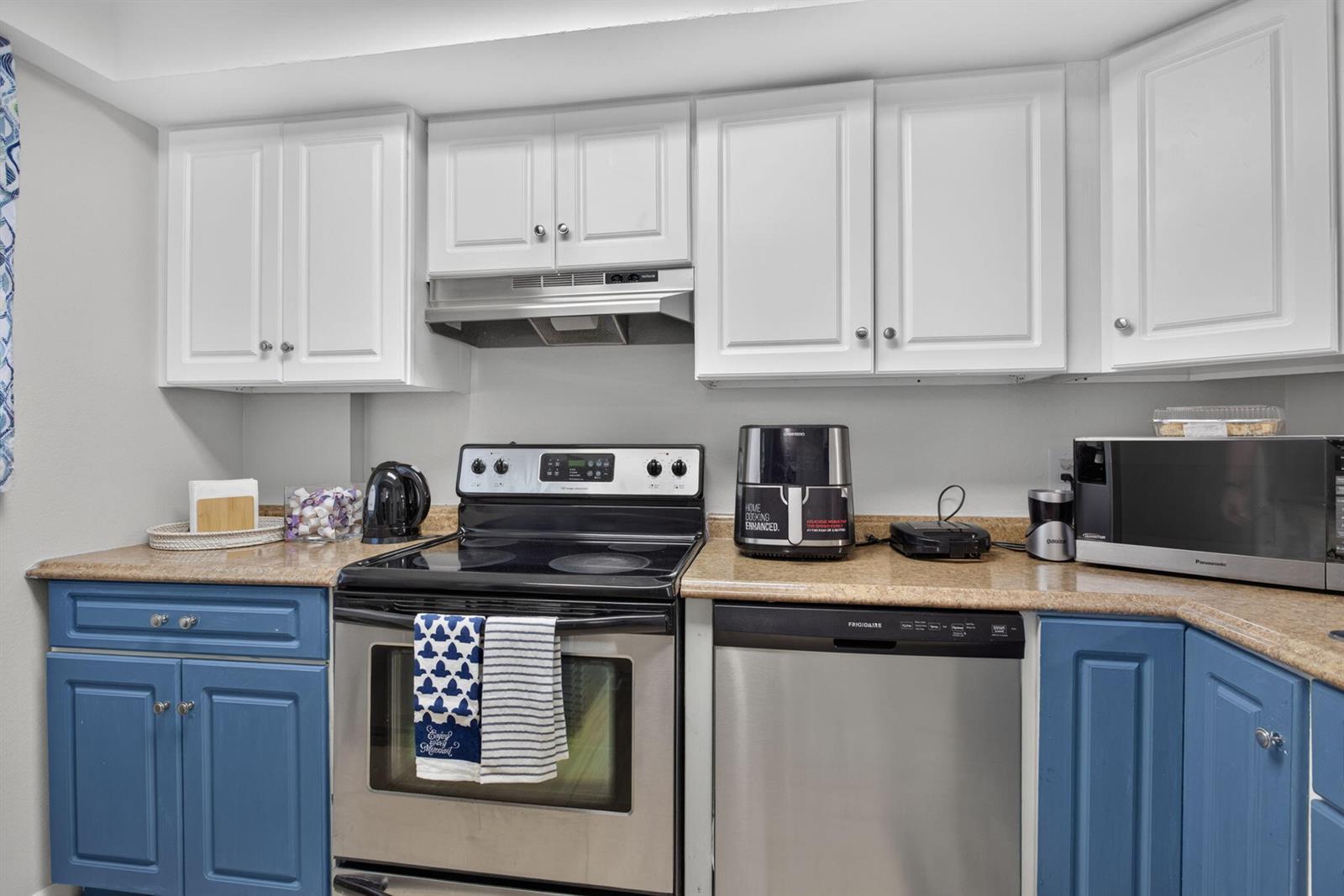 A kitchen features white upper cabinets, blue lower cabinets, stainless steel appliances, and tan countertops — 118 Royal Pk Drive # 1f, Oakland Park FL 33309, OAKLAND PARK, FL