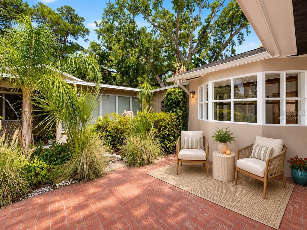 A patio with two chairs and a small table sits on a red brick floor — 8161 22ND AVENUE N, ST PETERSBURG, FL
