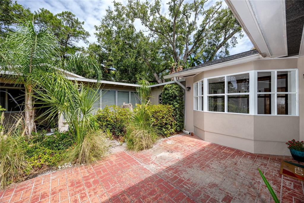 A brick patio sits in front of a house with a bay window and landscaping — 8161 22ND AVENUE N, ST PETERSBURG, FL
