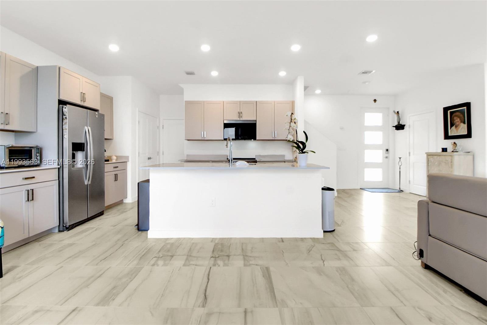 A modern kitchen features light-toned cabinetry, a central island, and large-format tile flooring — 1521 SE 7th Ct, Homestead FL 33033, HOMESTEAD, FL