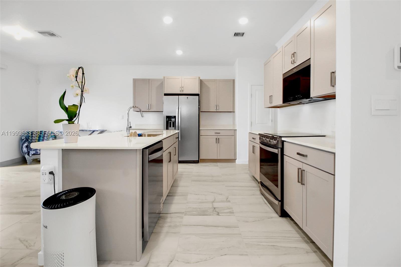 A modern kitchen features light-colored cabinetry, stainless steel appliances, and a large central island — 1521 SE 7th Ct, Homestead FL 33033, HOMESTEAD, FL