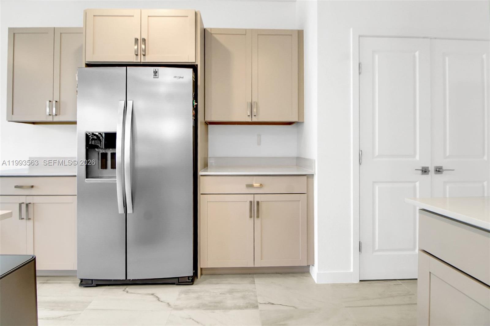 A kitchen features light-colored cabinets, a stainless steel refrigerator, and white countertops — 1521 SE 7th Ct, Homestead FL 33033, HOMESTEAD, FL