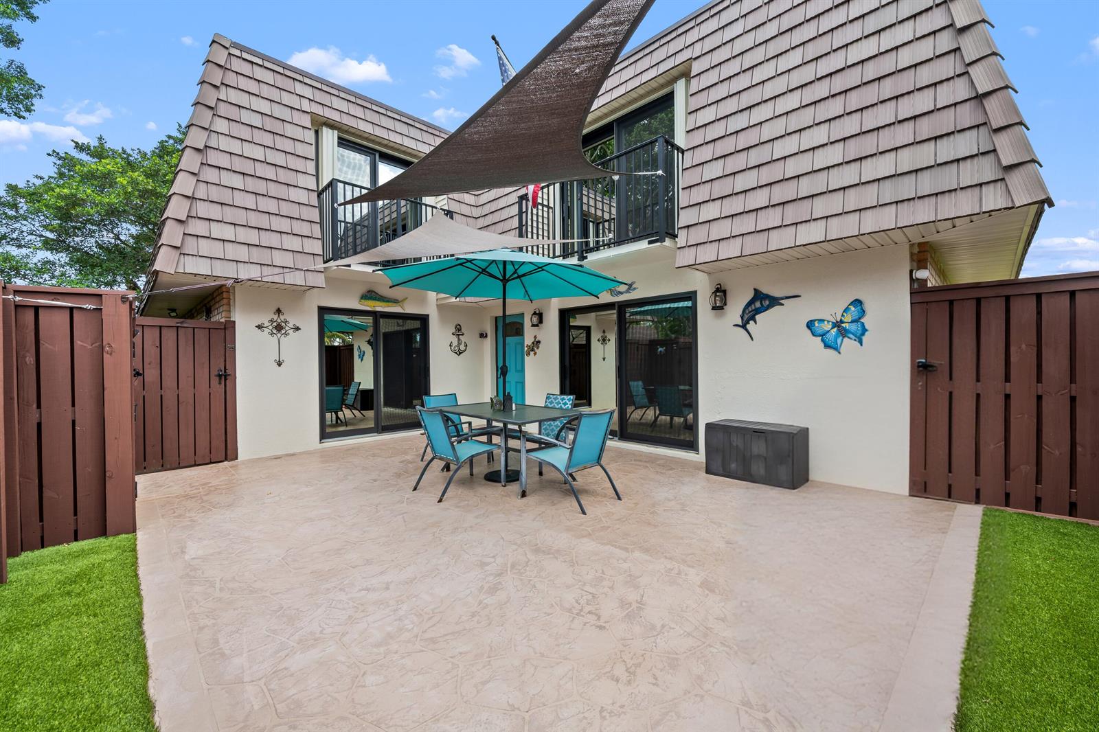 A patio with a dining set and umbrella sits in front of a two-story house — 2512 SW 15th Street, Deerfield Beach FL 33442, DEERFIELD BEACH, FL