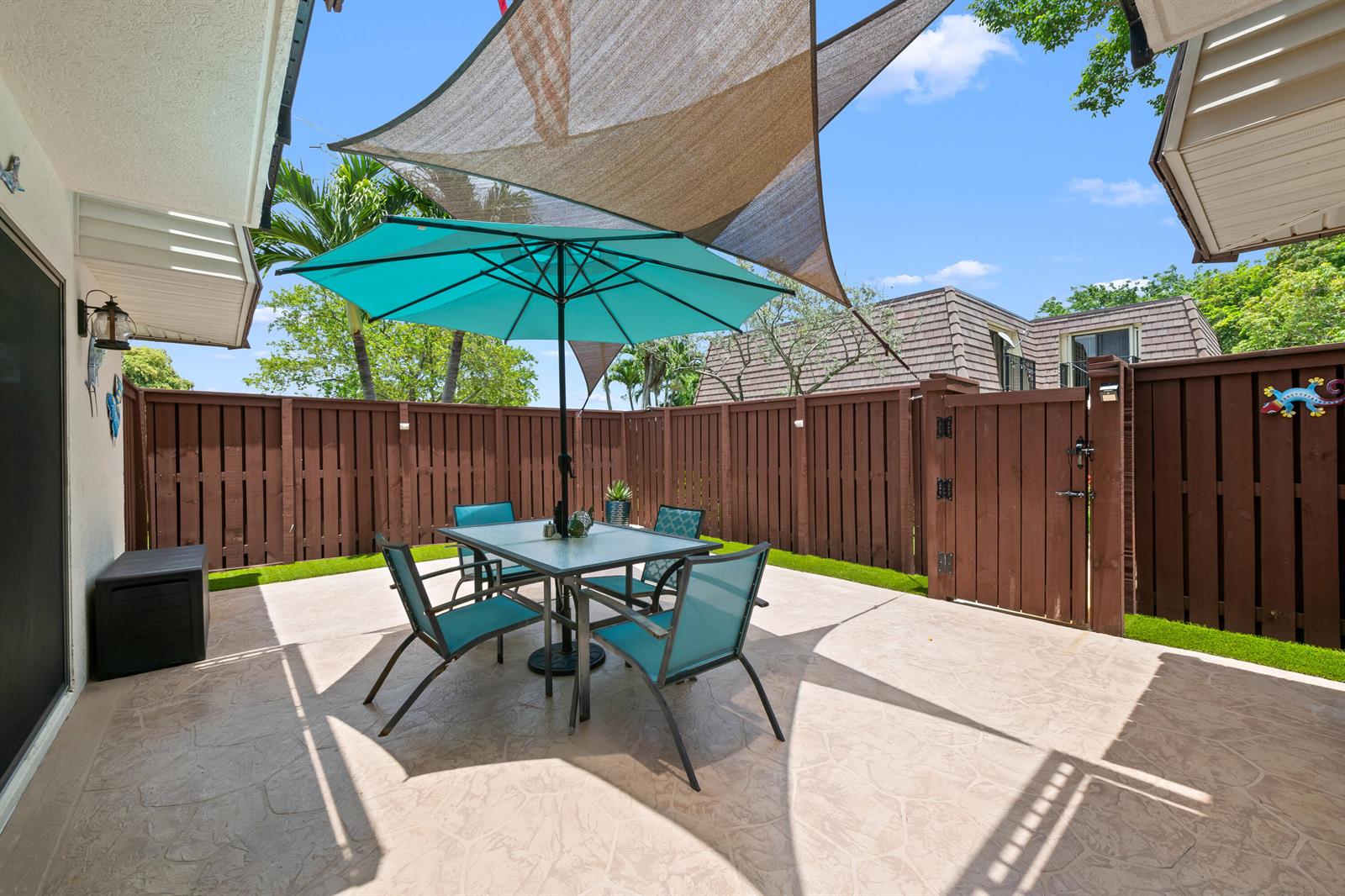 A patio features a dining set with a turquoise umbrella under a triangular shade sail — 2512 SW 15th Street, Deerfield Beach FL 33442, DEERFIELD BEACH, FL