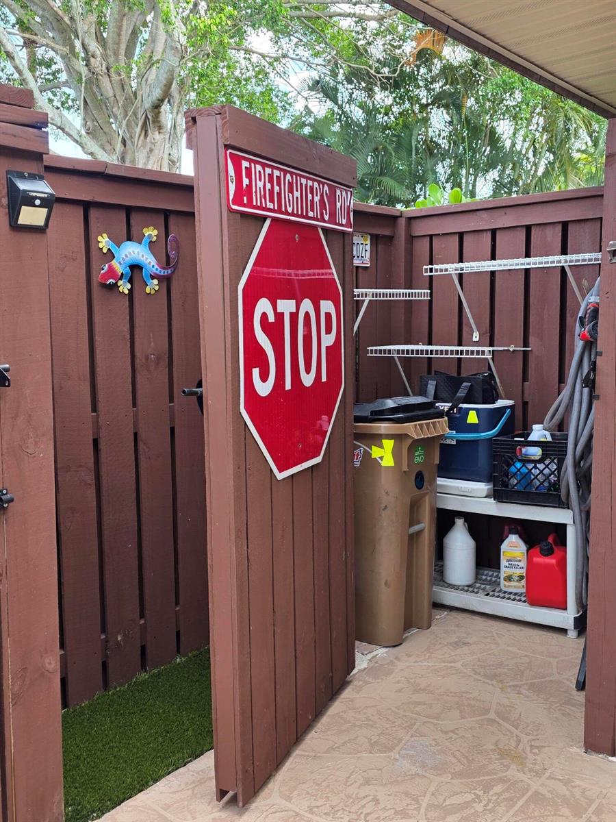 A brown wooden fence gate features a stop sign and a Firefighter's Road street sign — 2512 SW 15th Street, Deerfield Beach FL 33442, DEERFIELD BEACH, FL