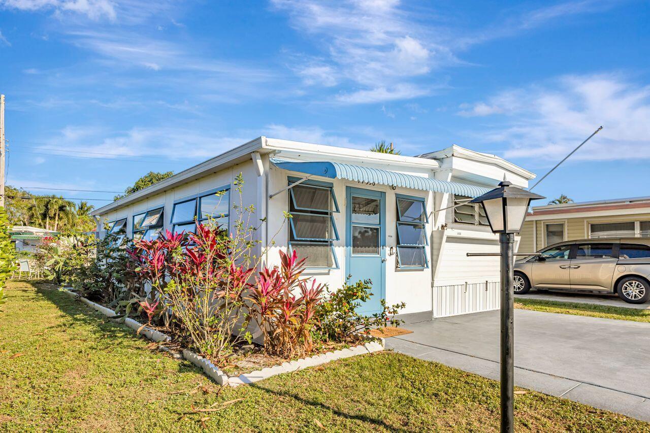 A white mobile home with a blue door and awning sits on a grassy lot — 14556 Glenview Drive, Delray Beach FL 33445, DELRAY BEACH, FL