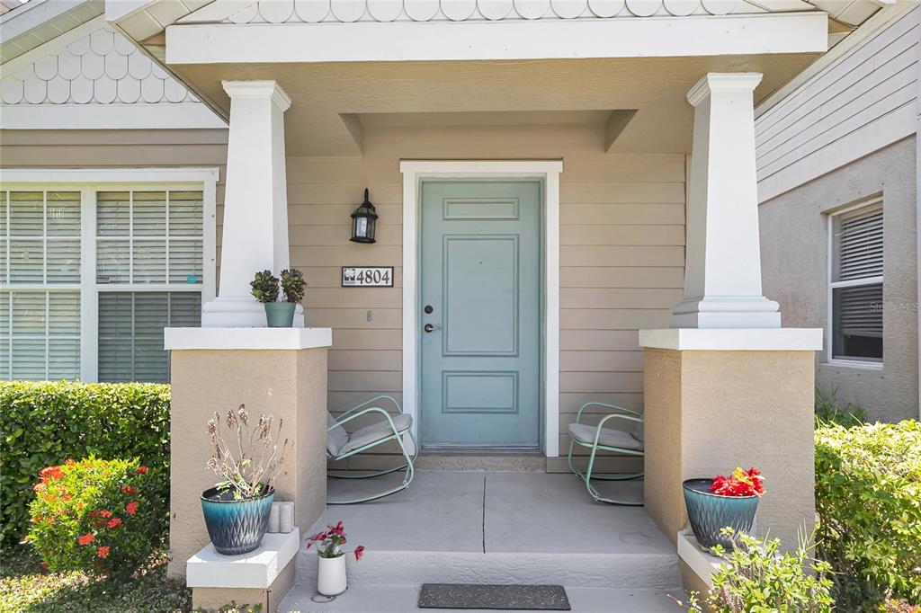 A light blue front door is centered on a covered porch with two rocking chairs — 4804 FOREST CREEK TRAIL, PARRISH, FL